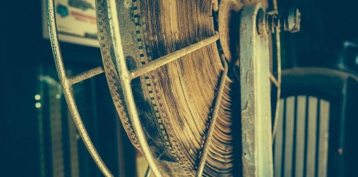 An old fashioned age-damaged film reel on a metallic spindle.