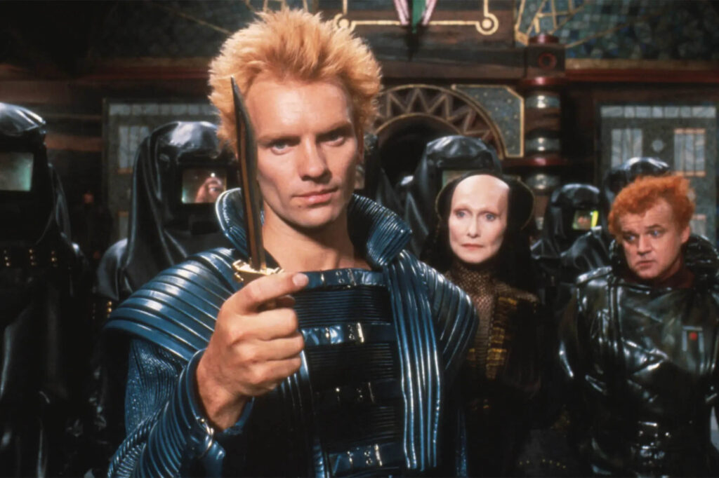 A man holding a sword and staring towards the camera.