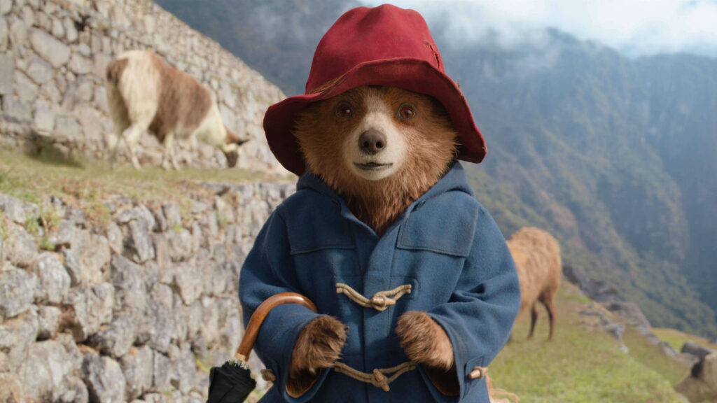 Paddington Bear stands in the Peruvian landscape looking towards the camera.